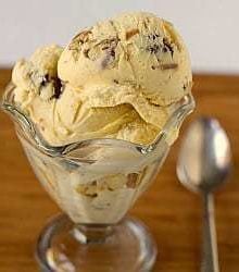 Scoops of date, rum, and pecan ice cream in a glass bowl with a spoon.