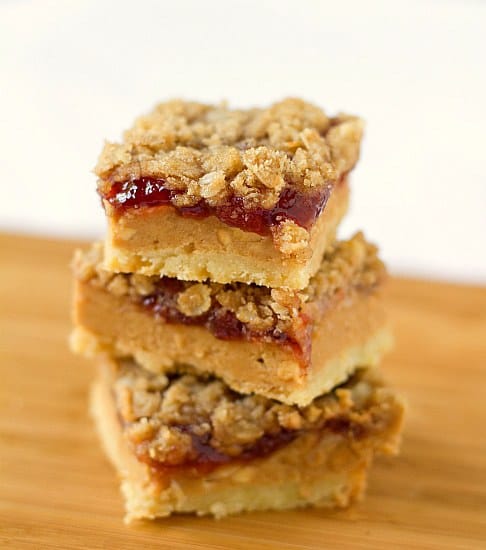 Stack of 3 peanut butter and jelly bars on a wood board.