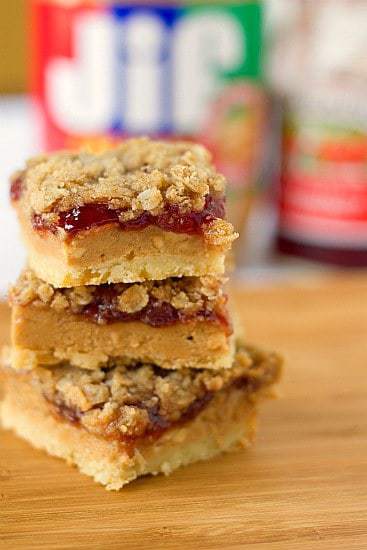 Stack of 3 peanut butter and jelly bars on a wood board.