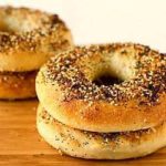 2 stacks of 2 everything bagels on a wood surface.
