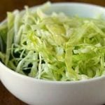Sliced cabbage with oil and vinegar in a white bowl.