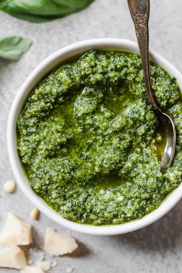 A bowl of homemade pesto with a spoon in it.