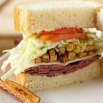 A homemade primanti brother's sandwich cut in half showing all of the sandwich ingredients.