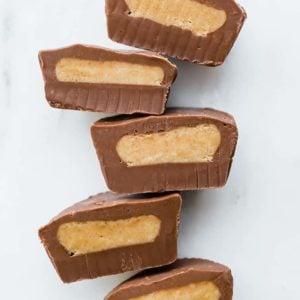 Multiple peanut butter cups cut in half, lined up, cut side up.