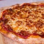 Pepperoni pizza on a wood cutting board after baking.