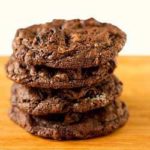 Stack of 4 triple chocolate Oreo chunk cookies on a wood board.