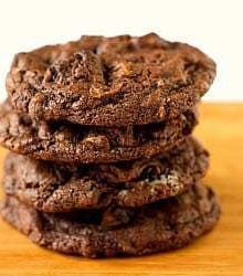 Stack of 4 triple chocolate Oreo chunk cookies on a wood board.