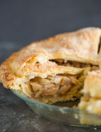 A fresh baked apple pie sliced into so you can see the filling.