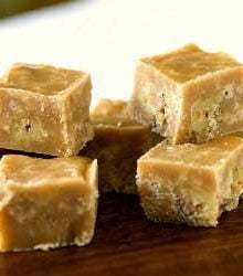 Squares of maple walnut fudge on a wood board.