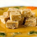 Squares of pumpkin fudge on a gold colored plate.