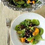 Overhead image of a serving of roasted butternut squash salad with cider vinaigrette in a white bowl with a fork.