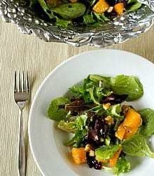 Overhead image of a serving of roasted butternut squash salad with cider vinaigrette in a white bowl with a fork.