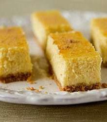 Side view of eggnog cheesecake bars on a white plate.