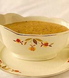 Homemade gravy in a gravy boat on a serving plate.
