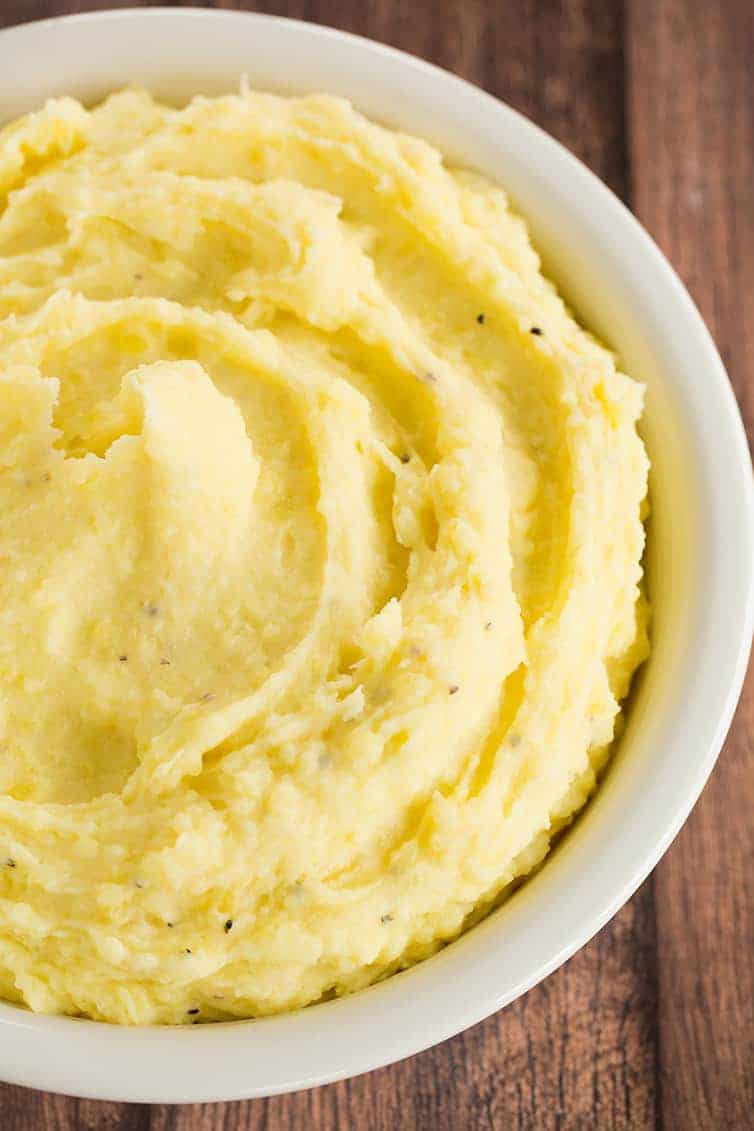 A bowl of mashed potatoes placed on a rustic wooden background.