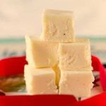 Squares of eggnog fudge stacked on a plate.