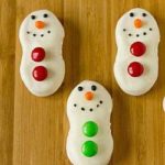 Nutter Butter cookies dipped in white chocolate and decorated like snowmen with M&Ms and frosting.
