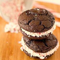 Stack of 2 chocolate peppermint whoopie pies on a wood board.