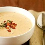 Cheddar cheese soup in a white bowl.