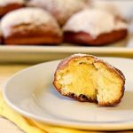 Half of a beignet on a white plate.