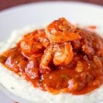 A serving of creole shrimp and grits in a white bowl.