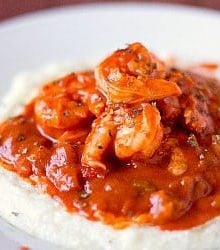 A serving of creole shrimp and grits in a white bowl.