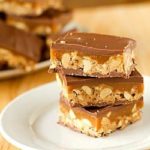 Stack of 3 homemade Snickers bars on a white plate.