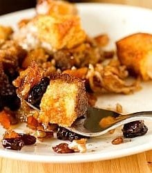 Serving of Mexican bread pudding on a white plate with a fork.