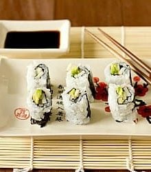 Sushi rolls on a white plate with chopsticks.