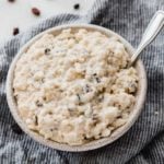 A bowl of rice pudding with raising on a dish towel.