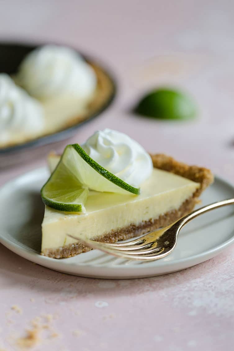 A slice of key lime pie with a dollop of whipped cream and lime garnish.