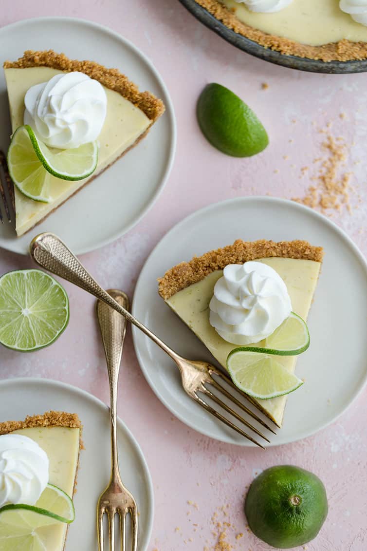 Individual slices of key lime pie on dessert plates with forks.