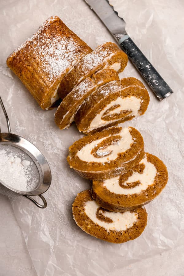 An overhead shot of sliced pumpkin roll with pieces laying cut-side down.