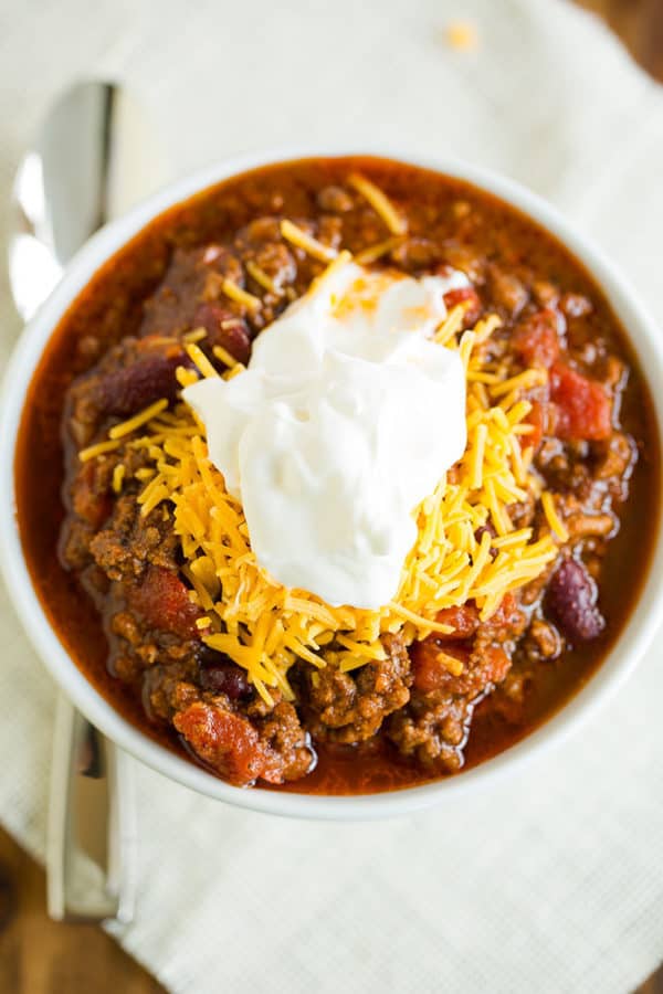 A big bowl of classic beef chili topped with shredded cheddar and sour cream.