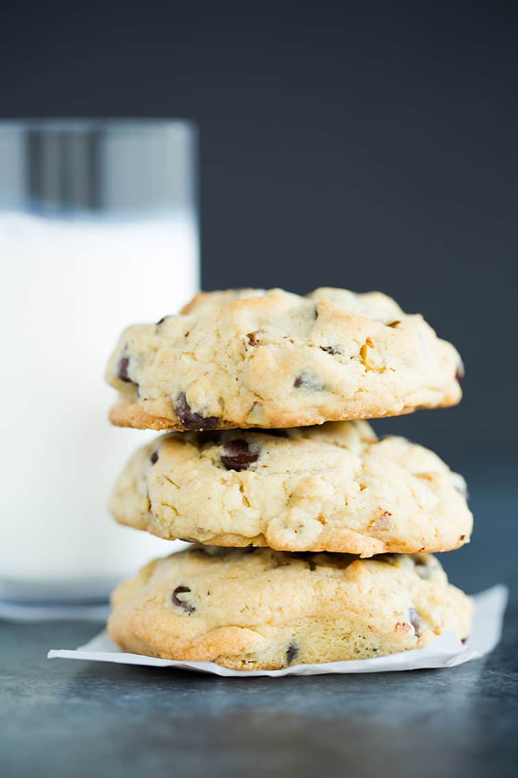 A stack of Levain chocolate chip cookies with a glass of milk.