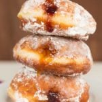 A stack of three paczki with fruit filling.