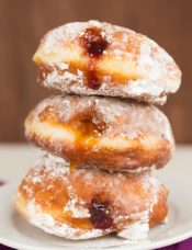 A stack of three paczki with fruit filling.