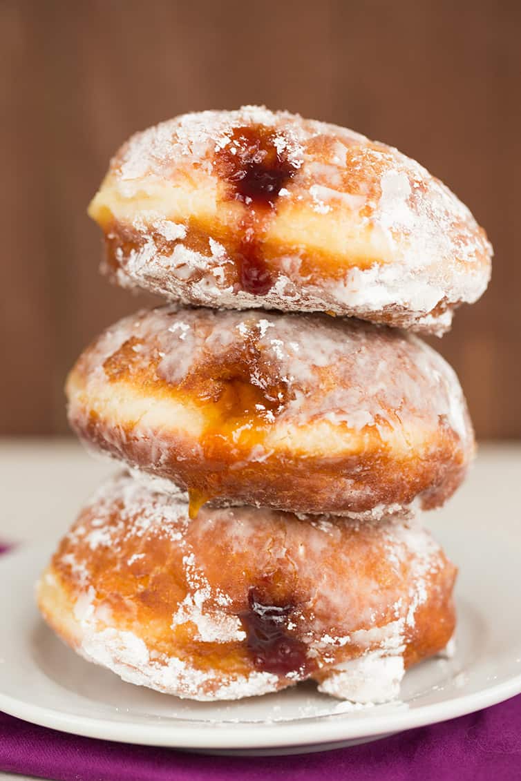 A stack of three paczki with fruit filling.