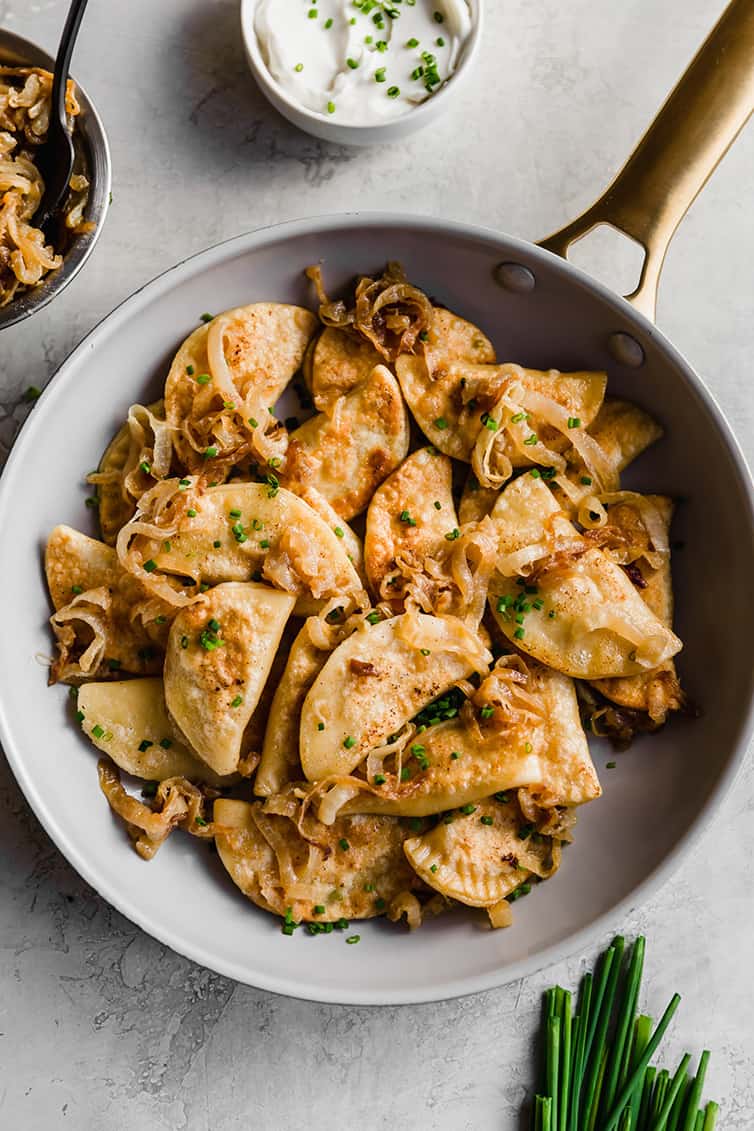 A frying pan full of pierogi with caramelized onion.