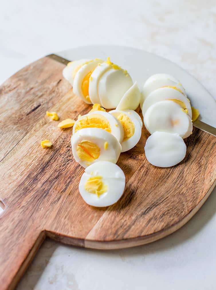 Sliced hard boiled eggs on a cutting board.