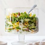 A glass trifle bowl with seven layer salad.