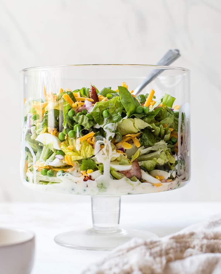 A glass trifle bowl with seven layer salad.