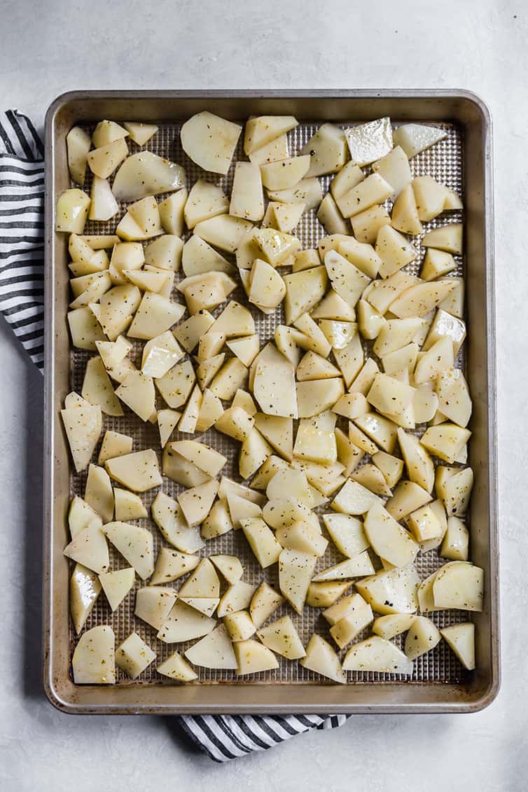 Pan of sliced potatoes tossed with olive oil and Italian seasoning.