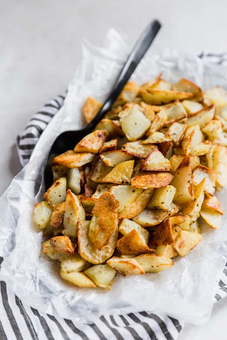 Bowl of roasted potatoes with a serving spoon.