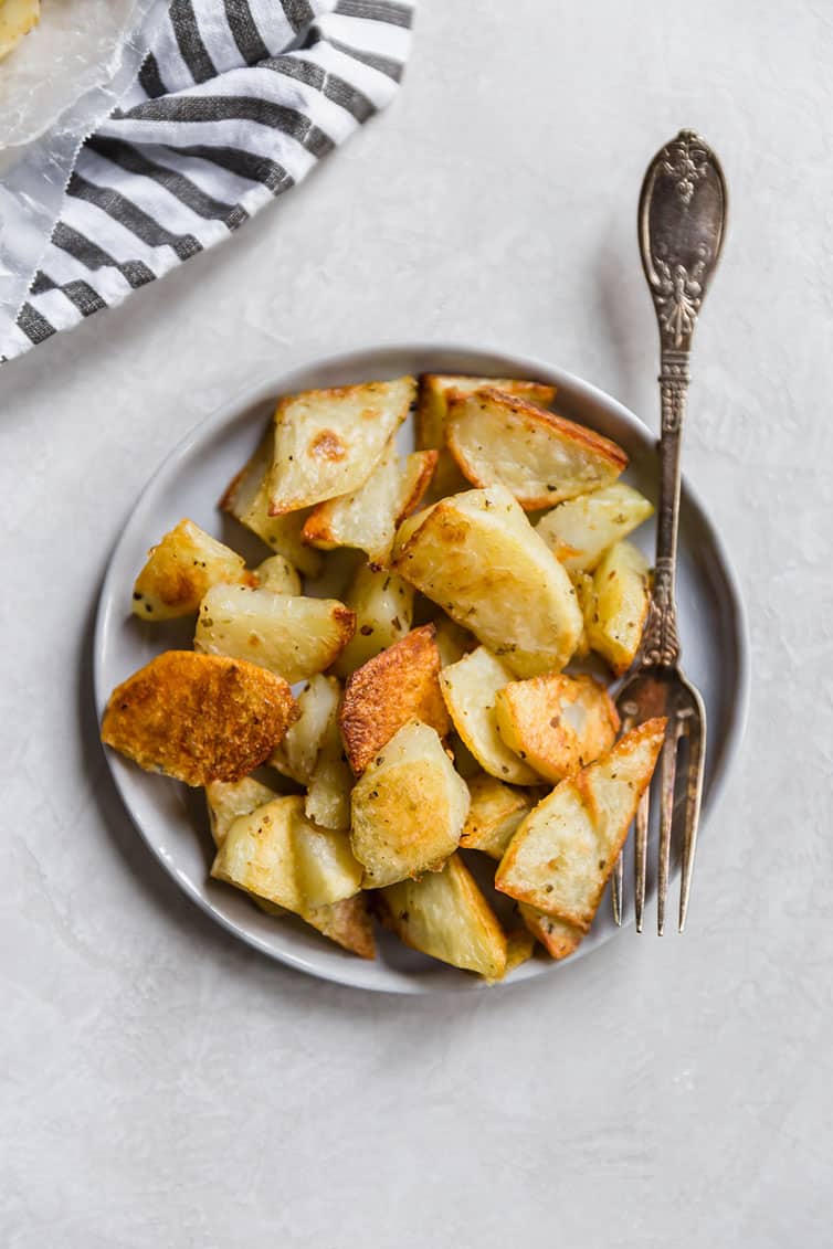 A plate of roasted potatoes with a fork.