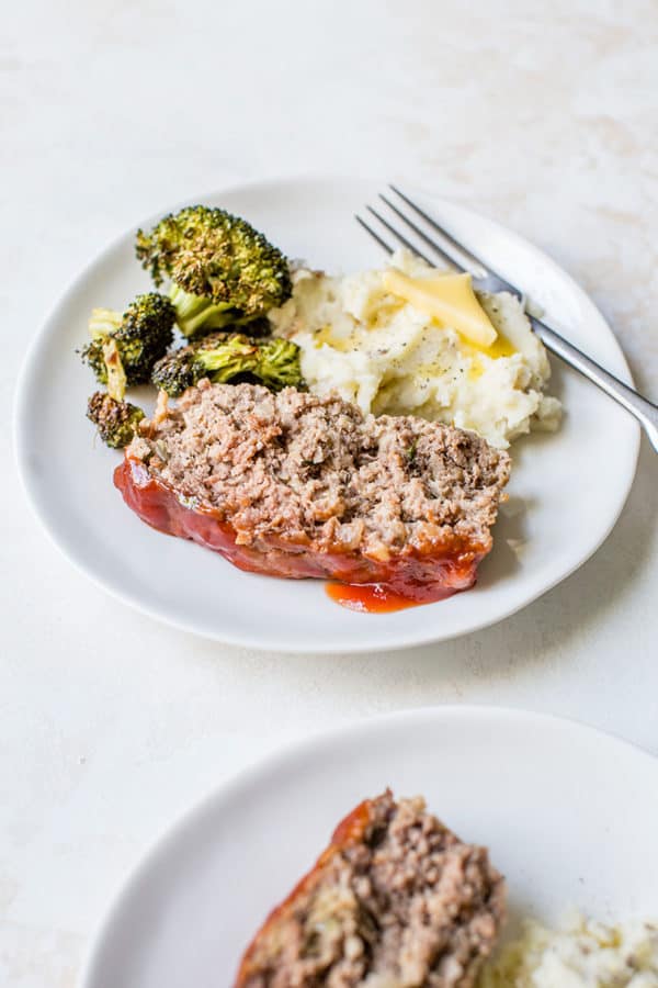 A plate with a slice of meatloaf, mashed potatoes and broccoli.