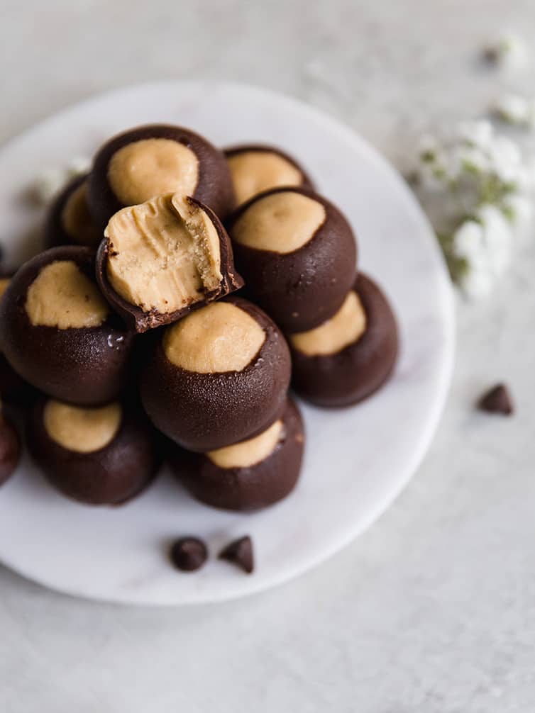 A mount of peanut butter buckeyes on a white plate.