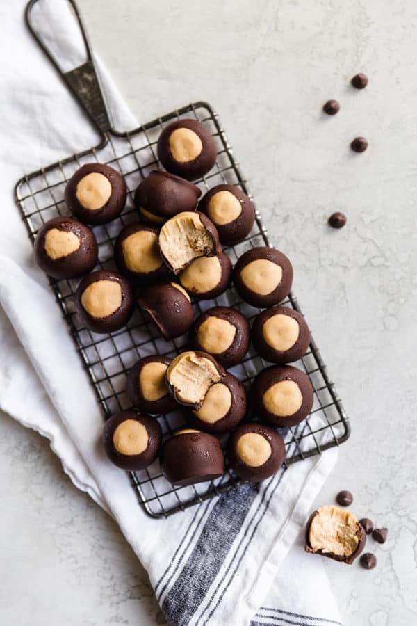 Peanut butter buckeyes on a wire rack, some bitten into.