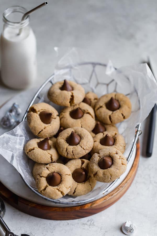 Peanut butter blossoms in a basket with a drink of milk.