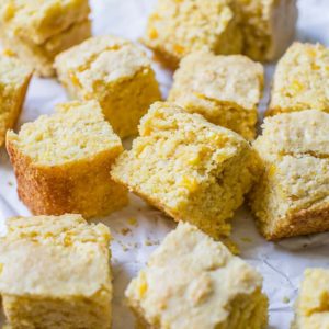 Squares of cornbread on a piece of parchment paper.